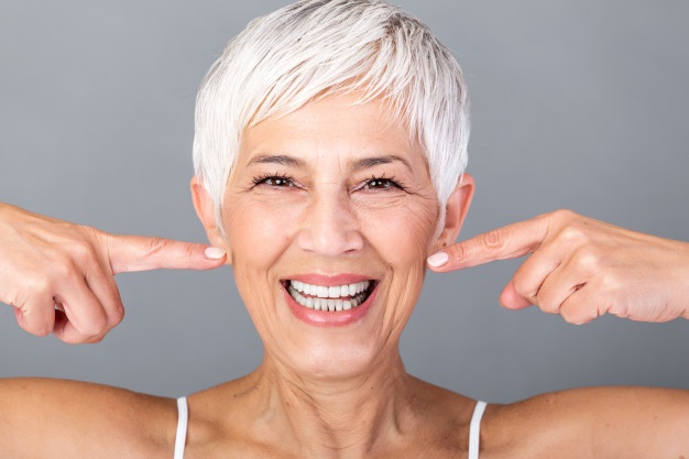 beautiful-caucasian-smiling-senior-woman-with-short-grey-hair-pointing-her-teeth-looking-camera-beauty-photography_1212-1670